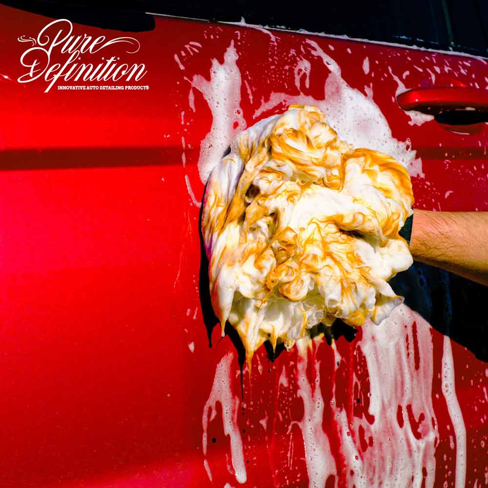 cleaning a red car with a wash mitt and soak ceramic shampoo