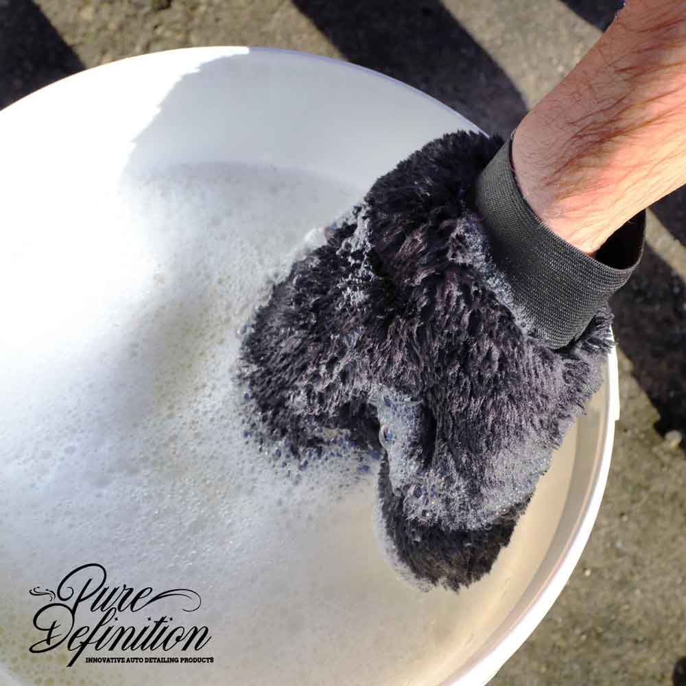 dipping synthetic wool wash mitt into bucket of car shampoo