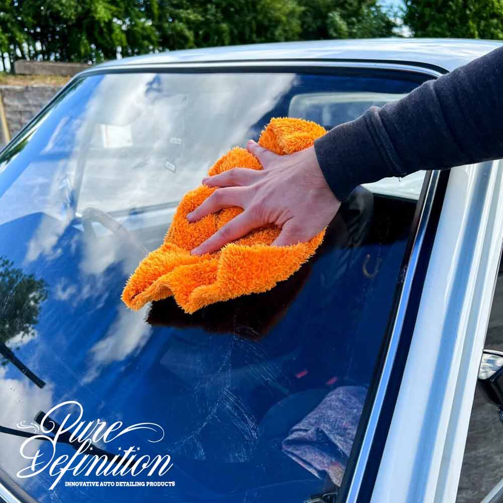 buffing the glass windscreen of a vw caddy, with an orange cloth