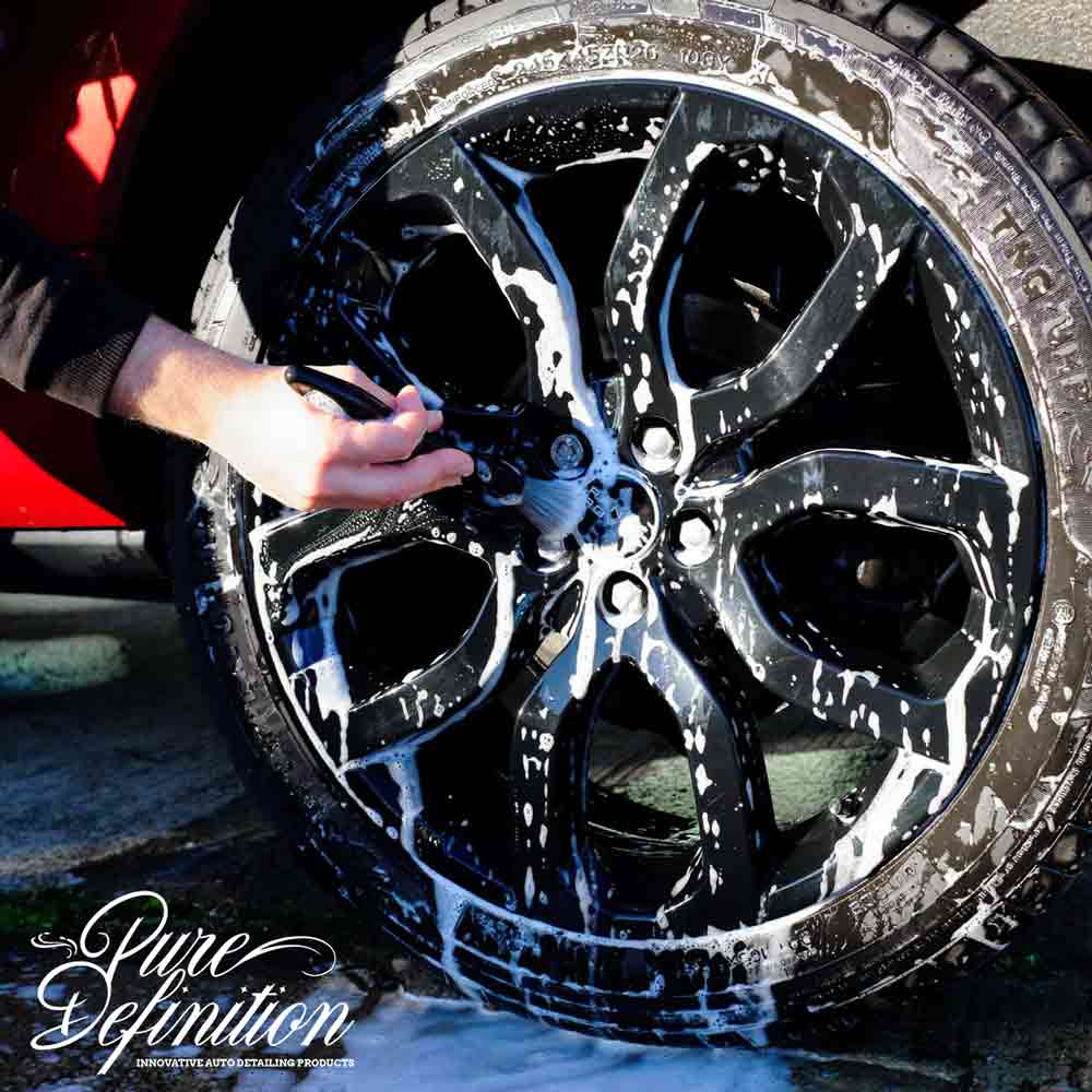 cleaning a black wheel with a brush